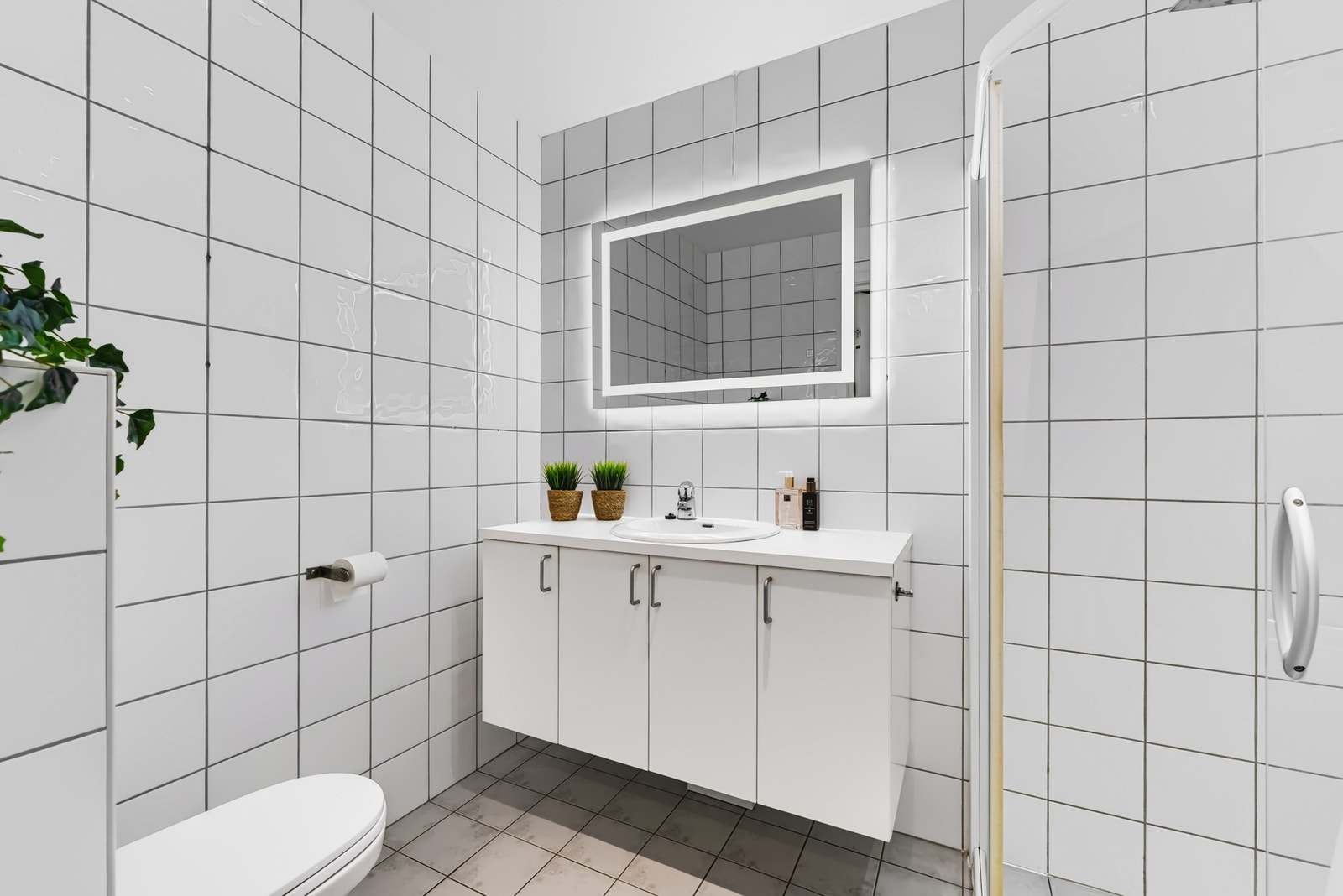 Lys baderomsinnredning med servant og speil med belysning. Galleribilde