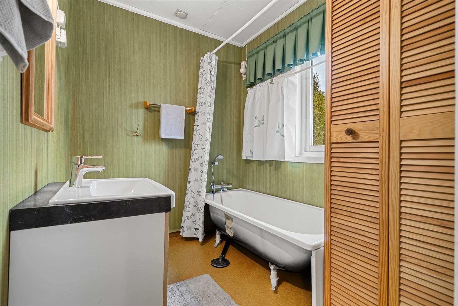 Bad i hovedetasjen innredet med badekar, baderomsinnredning og våtromsbelegg. Galleribilde