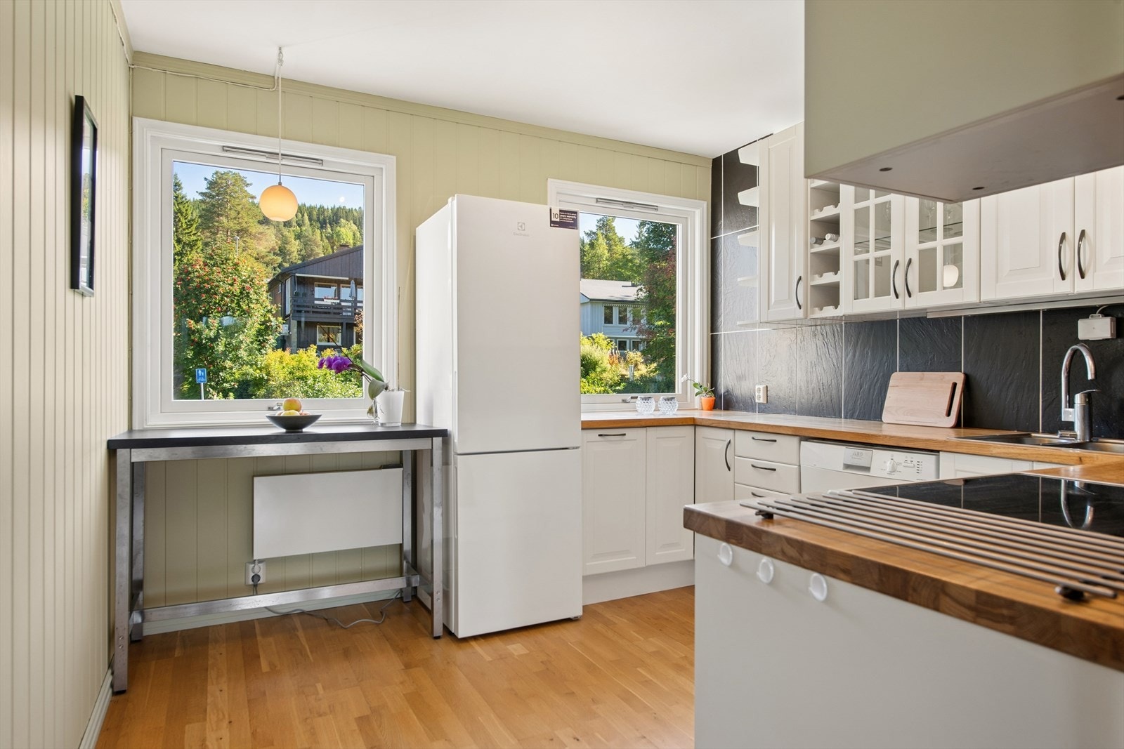 Kjøkkenet er innredet med profilerte fronter og heltre benkeplate. Enkelte overskap har glassfronter som tilfører innredningen et lett og luftig preg. Galleribilde