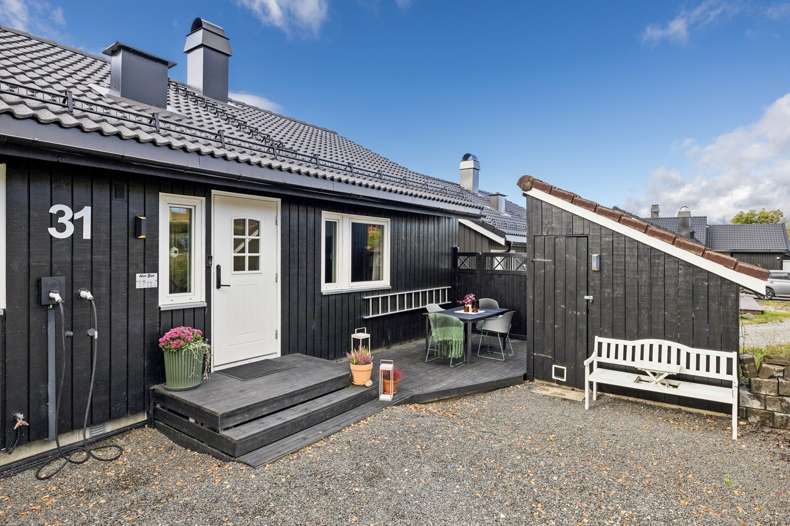 Inngangspartiet har en hyggelig markterrasse og direkte tilknytning til frittstående utebod på ca. 5 m2. Det er montert el-bil lader på husvegg. Galleribilde