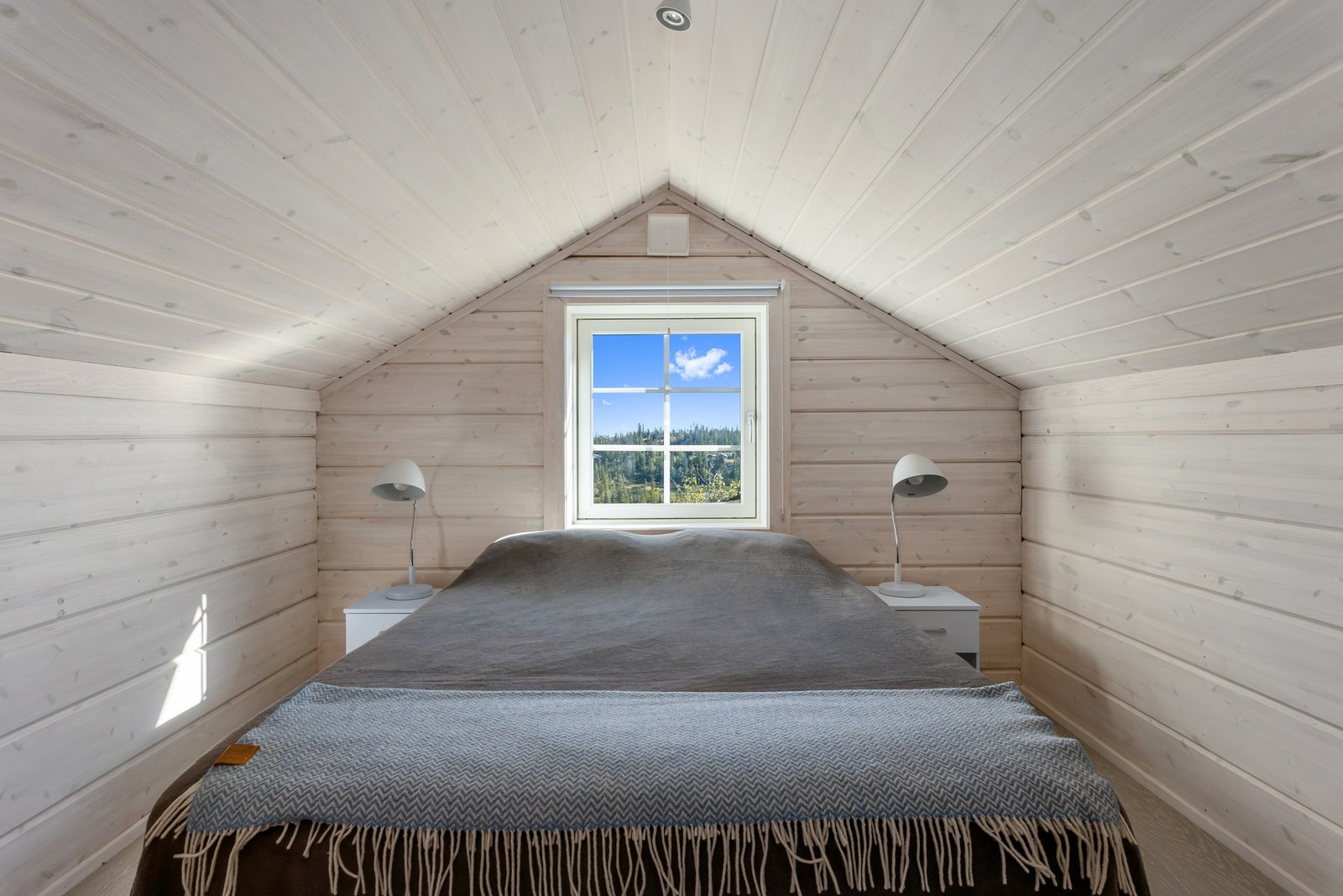 Videre fra loftstuen finner du dette koselige soverommet, med skrå himling, lune panelflater og flott utsyn mot naturen. Galleribilde