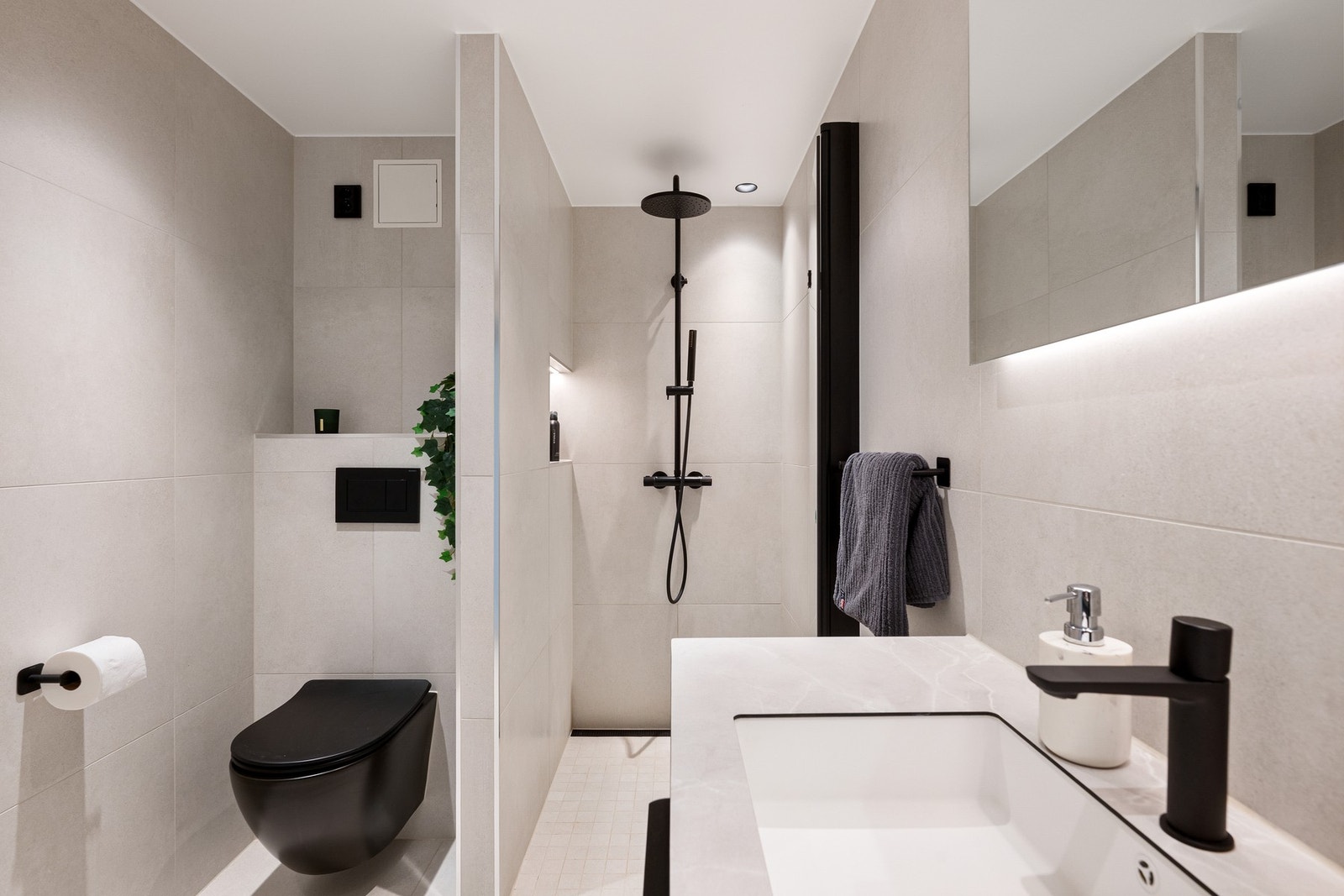Badet er innredet med vegghengt toalett, servantinnredning, dusjsone og opplegg for vaskemaskin. Galleribilde