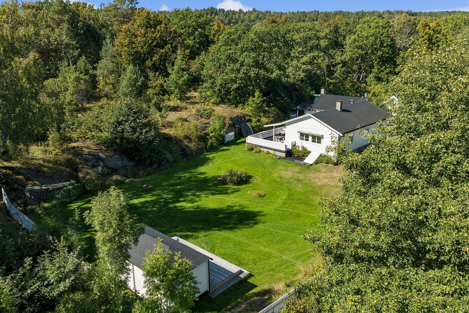 Dronefoto som viser eiendommens flotte plassering i grønne omgivelser. Galleribilde