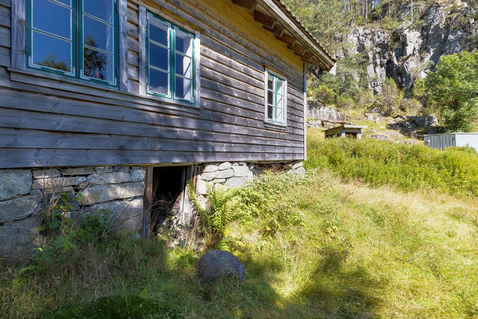 Detaljbilde av fasade og grunnmur som viser hyttas tradisjonelle utførelse. Galleribilde