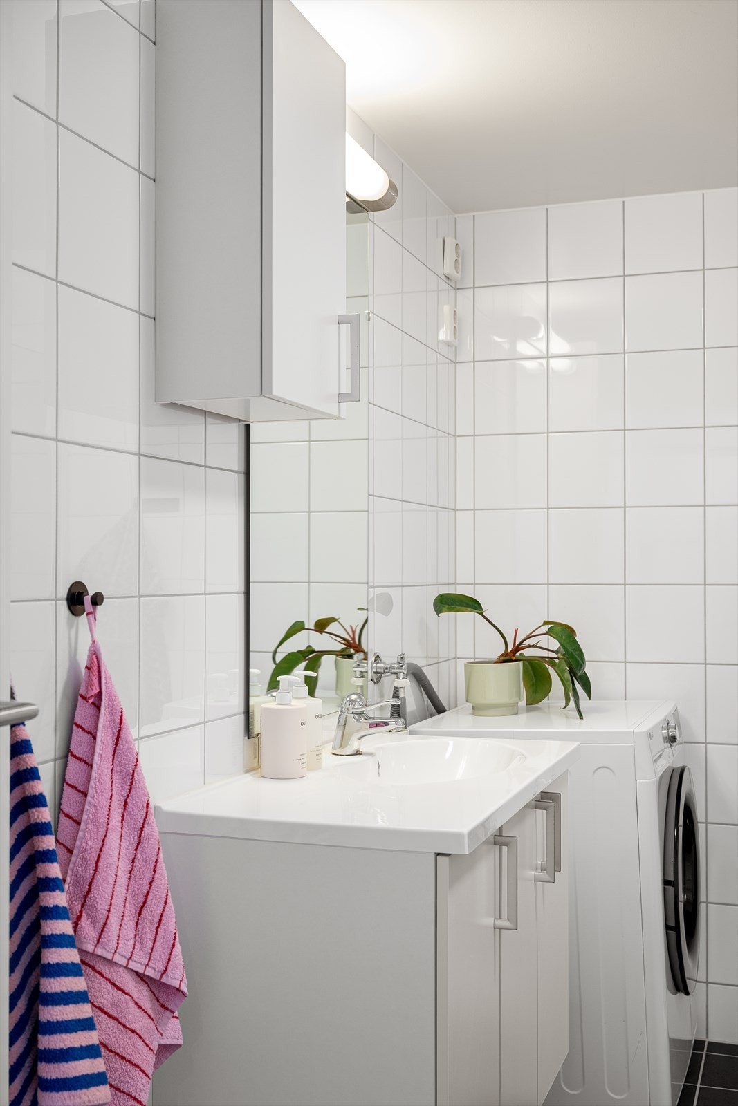 Servantinnredningen byr på praktisk oppbevaring, mens det er tilrettelagt for vaskemaskin ved siden av. Galleribilde
