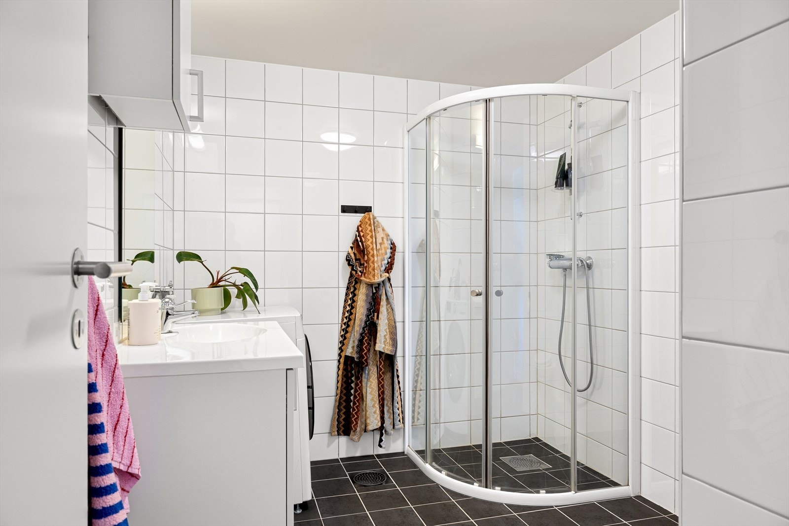 Badet er funksjonelt innredet med dusjkabinett, servantseksjon og opplegg for klesvask. Galleribilde