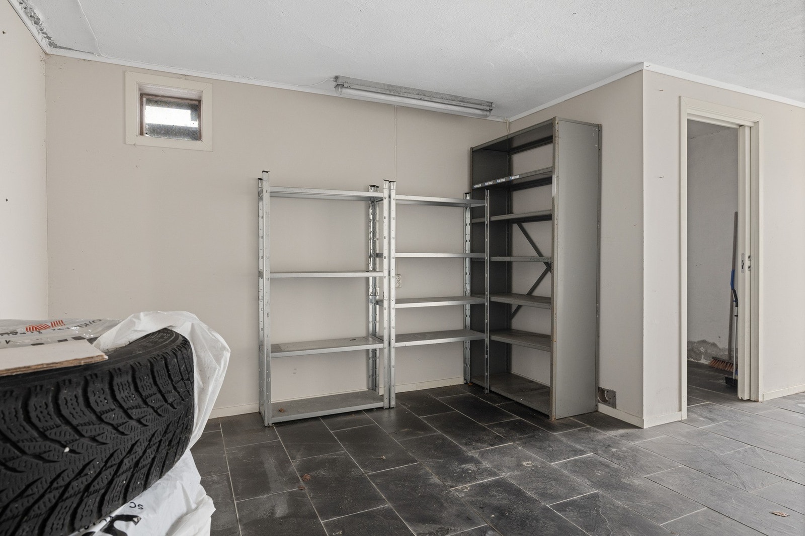 Carport ved inngangen i underetasjen. Her er gulvet flislagt og det er plass for lagring. Galleribilde