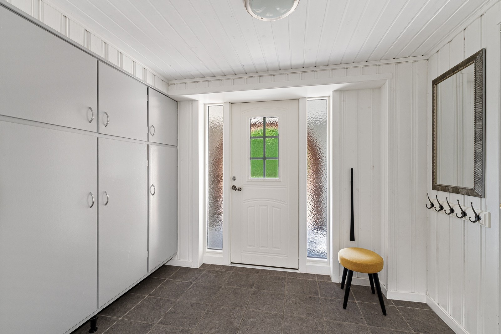 Velkommen inn! I både vindfang og gang er det vannbåren varme i gulvet. Fra vindfanget er det dør inn til det som i dag brukes som kjellerstue, og videre dør ut til garasjen. Galleribilde