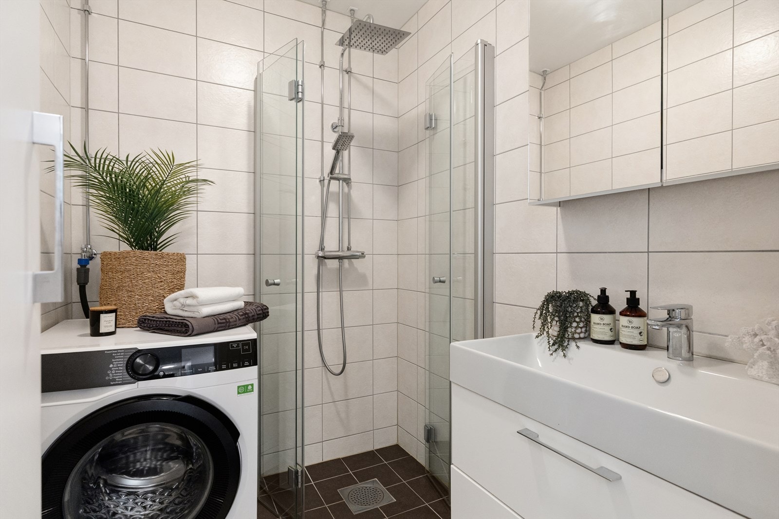 På det flislagte badet med varme i gulvet består innredningen av servant, speilskap, dusjhjørne og opplegg for vaskemaskin Galleribilde