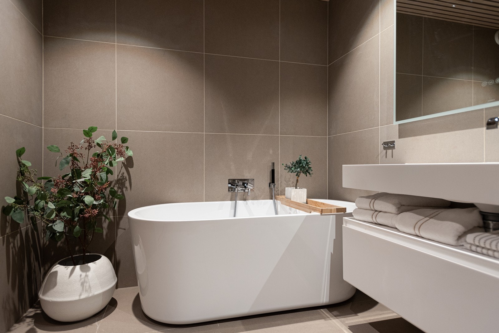 Badet er innredet med baderomsmøbler fra Corian, vegghegt wc, frittstående badekar, dusj med spesialtilpasset glassfelt og Tapwell kraner integrert Galleribilde