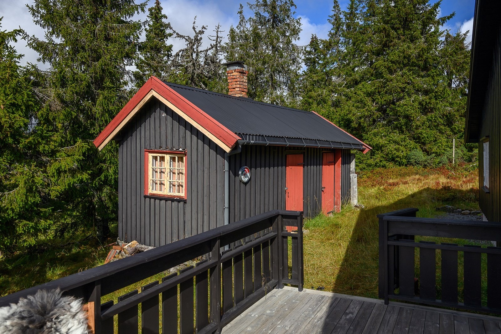 Frittstående, enkelt uthus på tomten gir praktisk lagringsplass for ved, ski og utstyr. Galleribilde