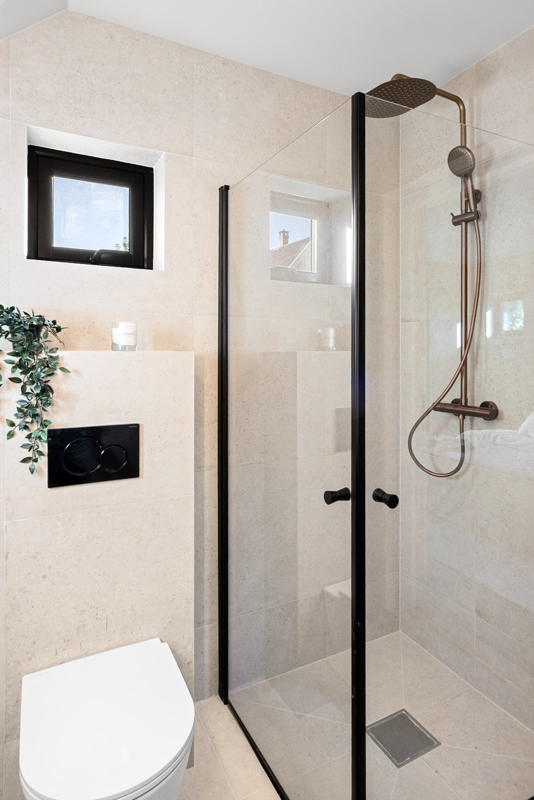 En suite bad har detaljer i sort og bronse, og dusjhjørne med glassdører. Galleribilde