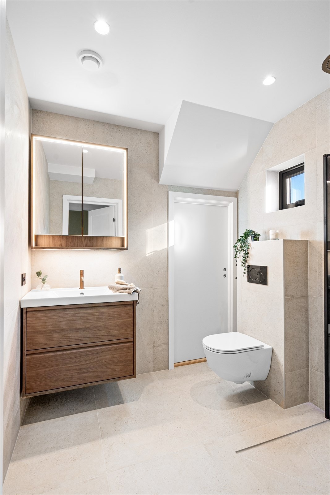 Badene har fliser i en varm fargetone, downlights og gulvvarme. Galleribilde