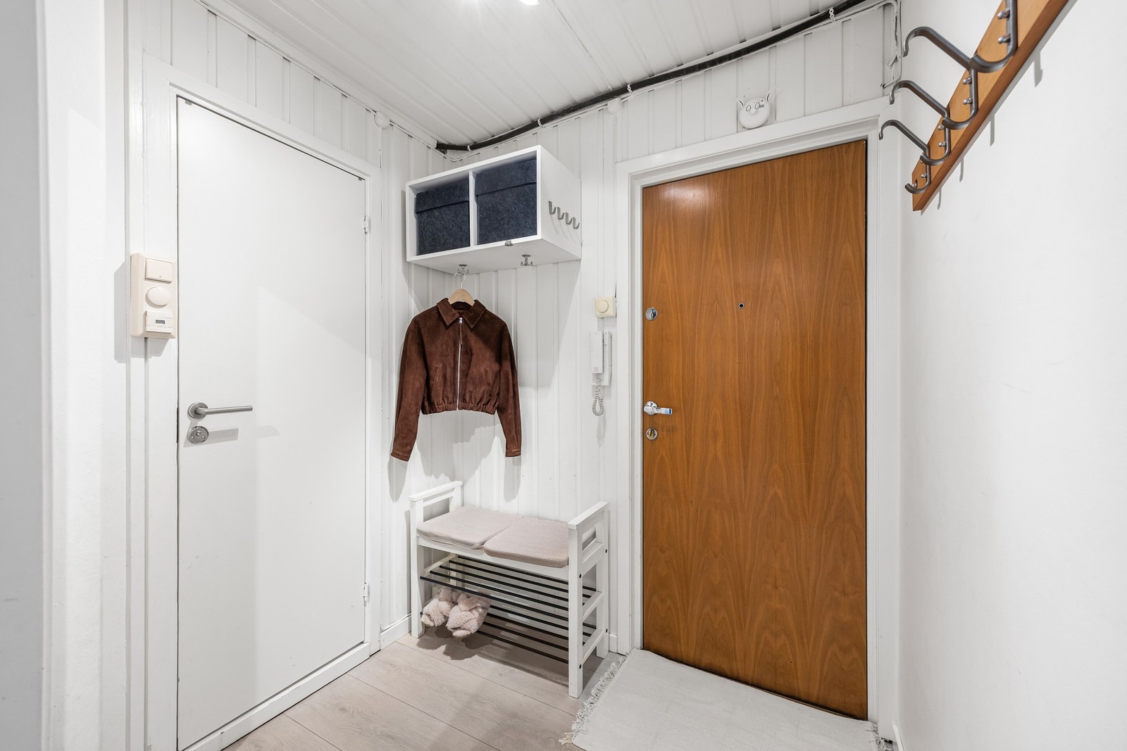 Entréen er innbydende med lyst panel og plass til oppheng av yttertøy på vegghengte knagger. Galleribilde