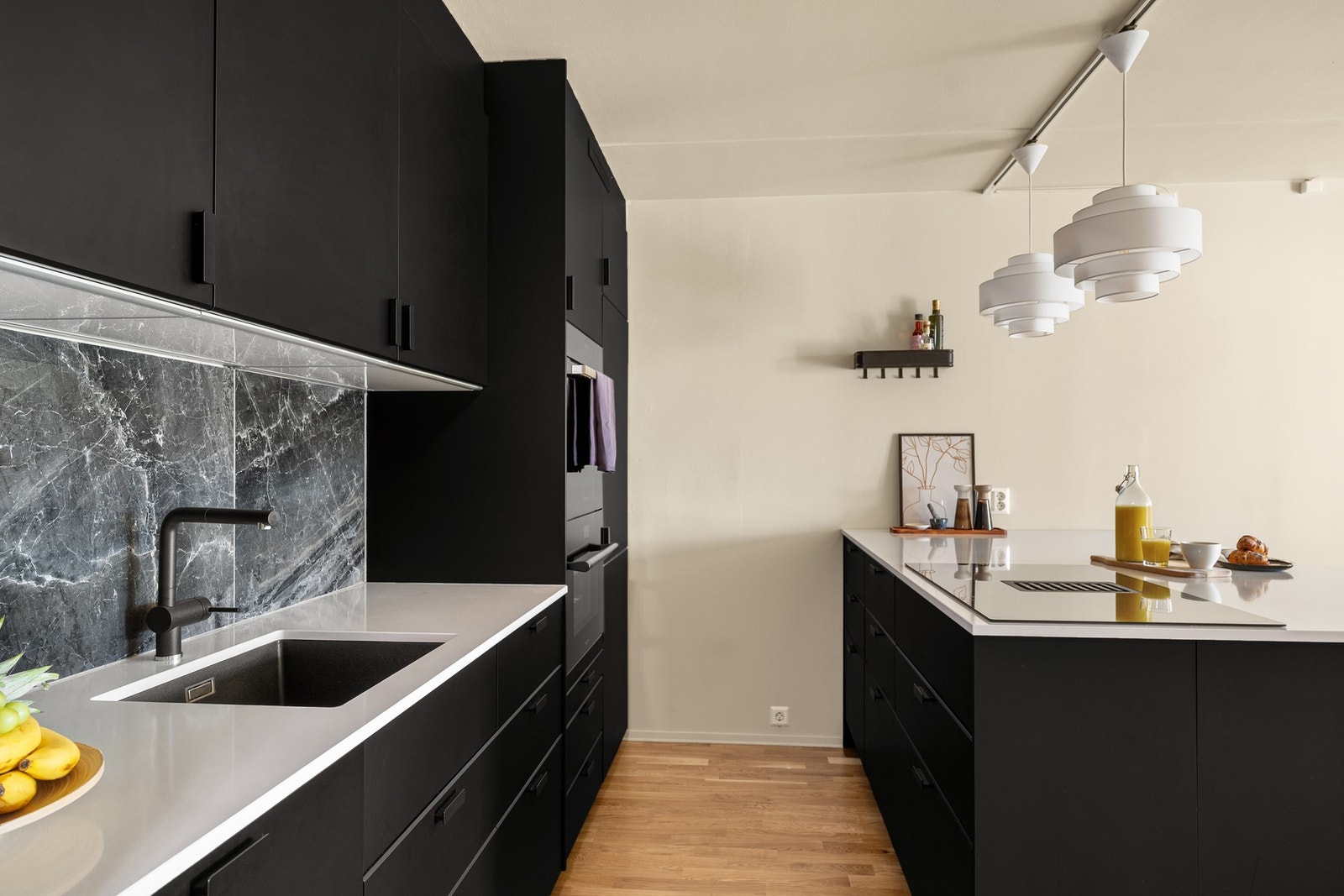 Her får du et gjennomført kjøkken med en sømløs og stilren helhet. Induksjonstopp med integrert avtrekksvifte gir en stilren og praktisk løsning som holder kjøkkenet visuelt ryddig. Galleribilde