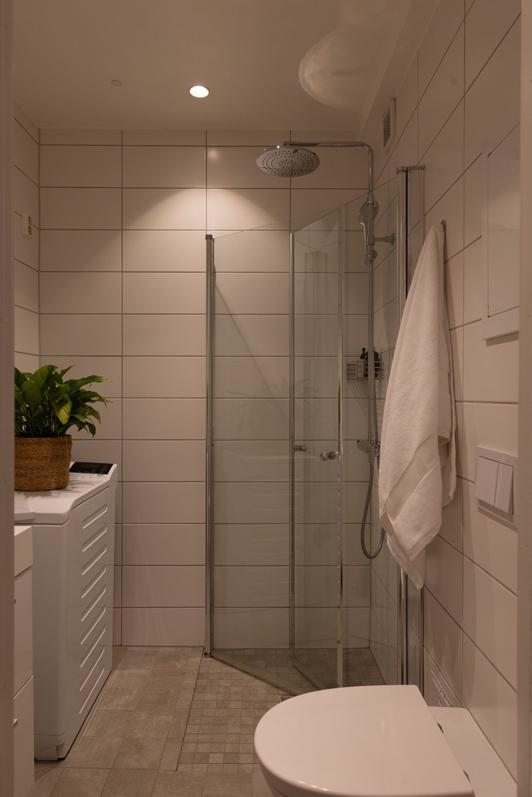 Badet er innredet med servantinnredning med oppbevaringsplass, speilskap, veggmontert toalett og dusjhjørne med glassvegger. Galleribilde