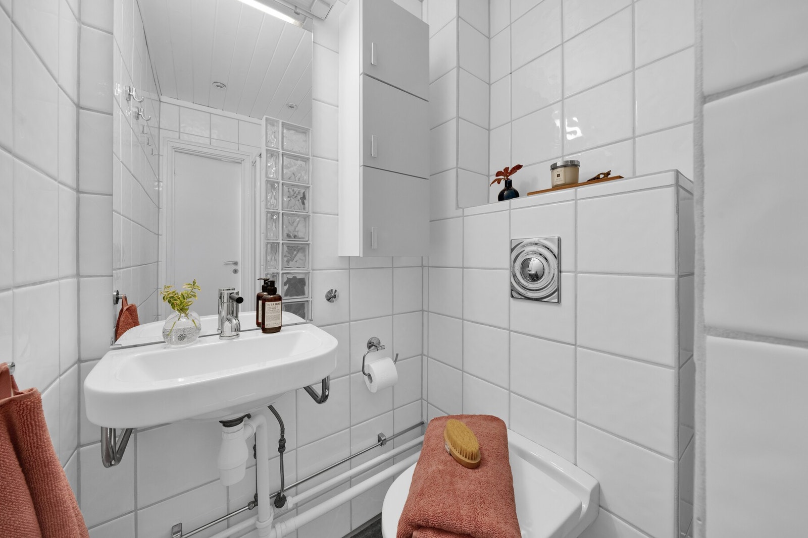 Våtrommet har vegghengt servant, veggmontert toalett og dusjvegger av glassbyggestein med skyvedør. Galleribilde