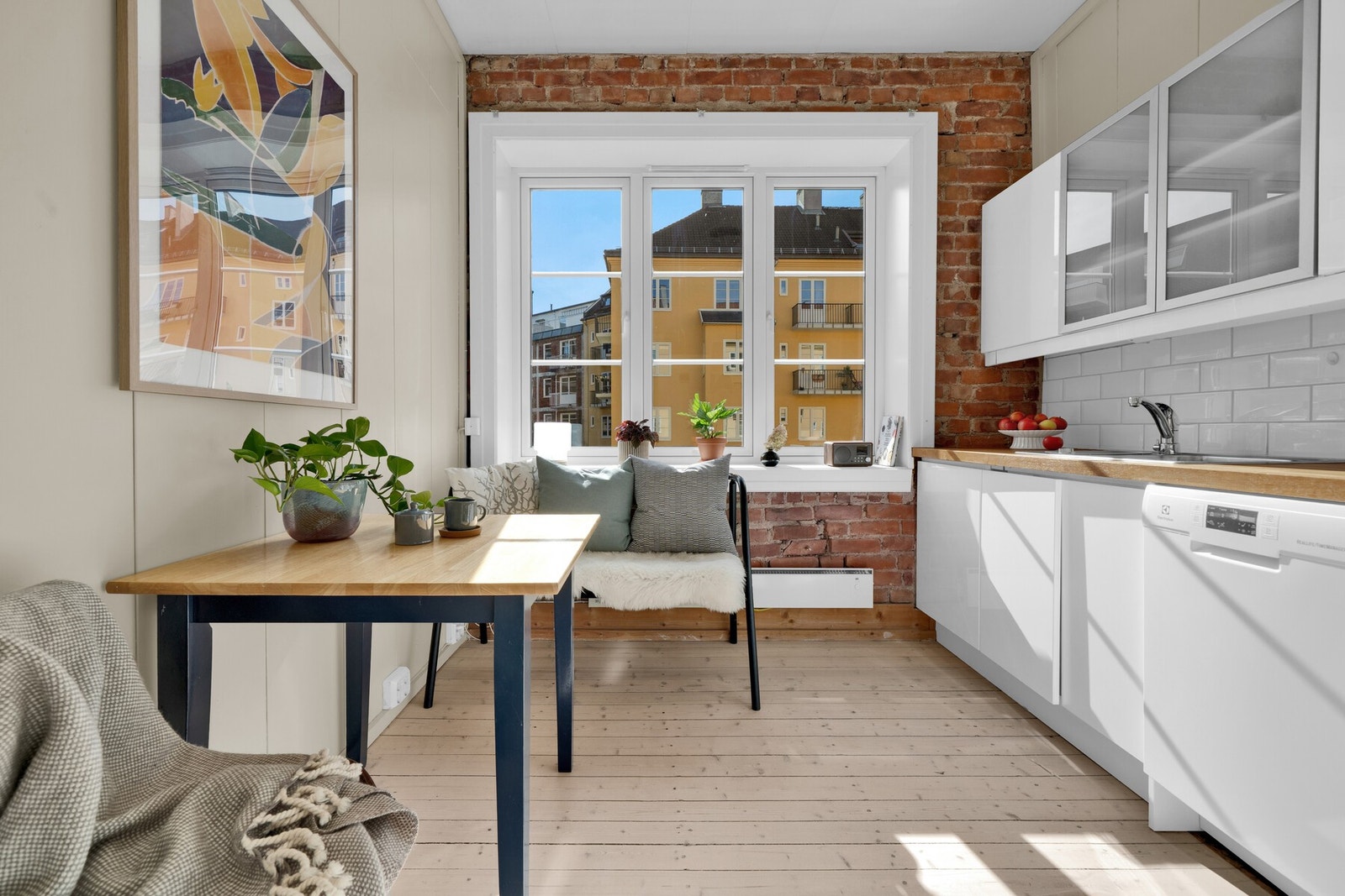 Stort, lyst kjøkken med god spiseplass! Stilren innredning og stilig teglsteinsvegg. Sjarmerende originale tregulv. Galleribilde