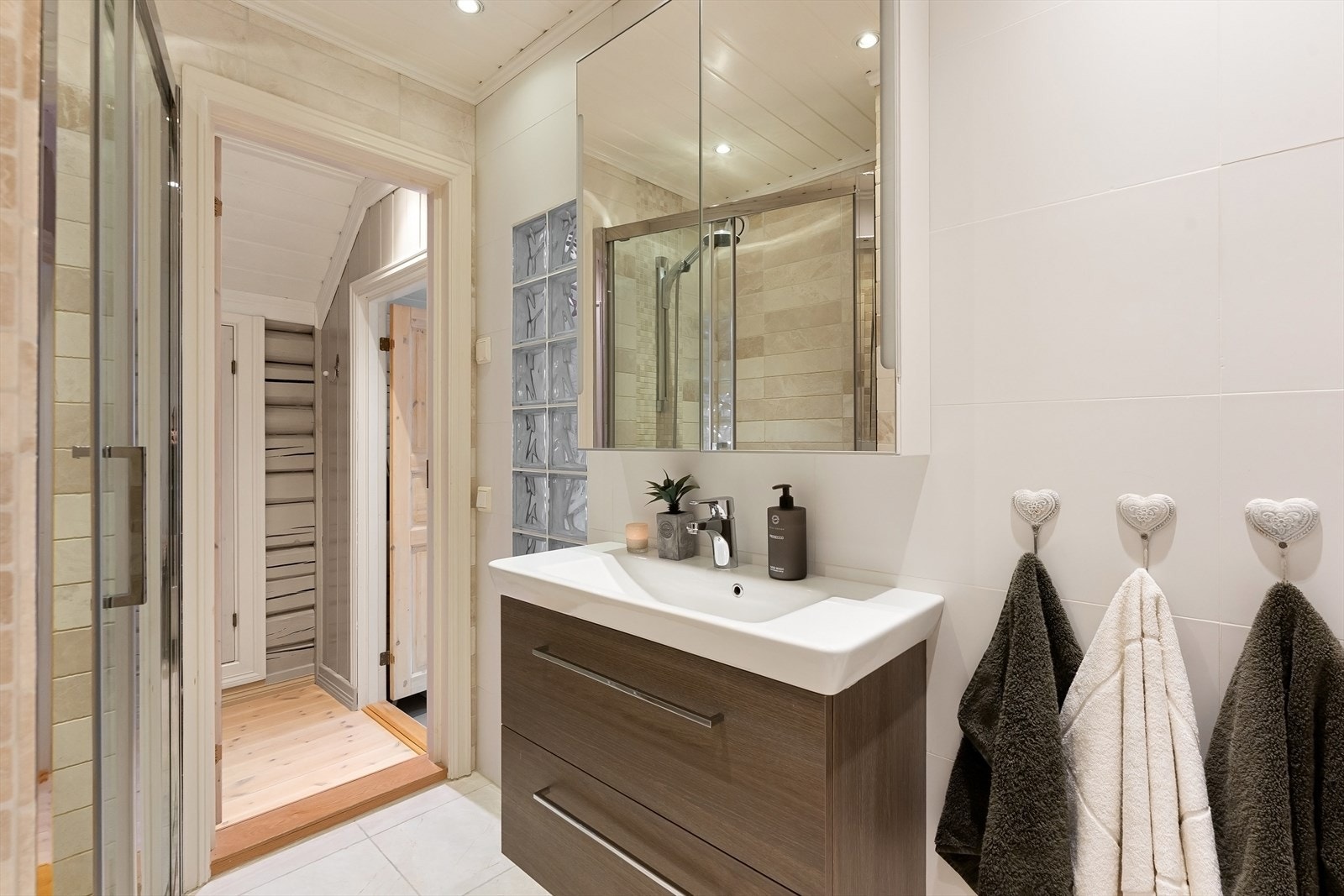 Bad i boligens 2. etasje med et lyst og moderne uttrykk. Rommet har flislagt gulv med varmekabler og lyse flislagte vegger, kombinert med detaljer i beige naturtoner som gir badet et lunt preg. Galleribilde