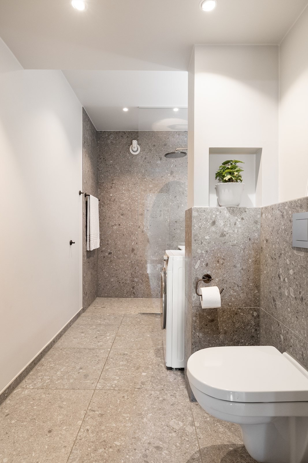 Badet er innredet med dusjnisje med glassvegg i herdet glass og hånd- og regndusjarmatur fra Grohe, veggmontert toalett og baderomsmøbel på 60 cm med profilerte fronter, overlimt servant med ettgrepsarmatur fra Grohe og vegghengt speil. Galleribilde