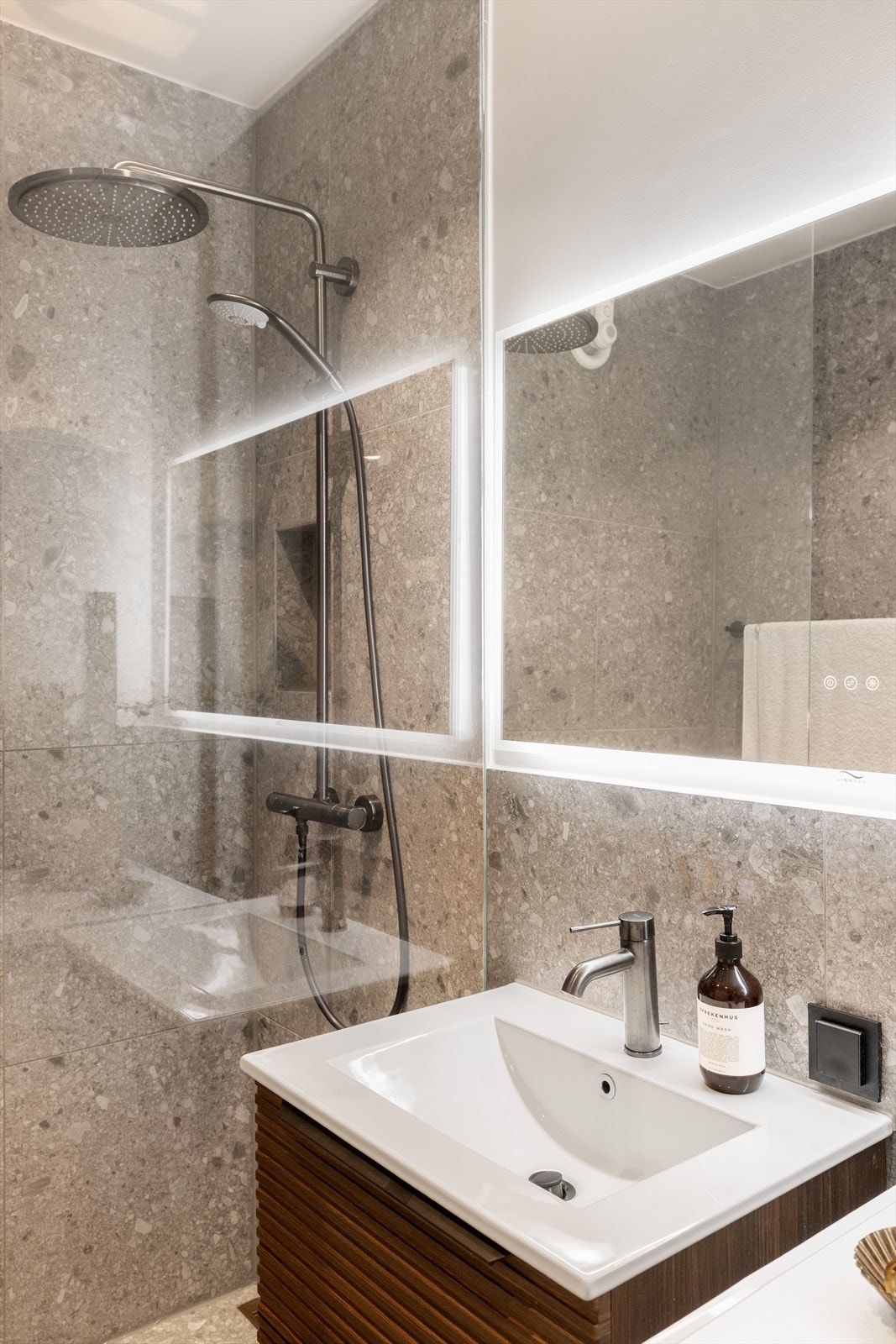 Badet har overflater med moderne 60 x 60 cm fliser på gulv, en kombinasjon av flislagte og malte vegger, elektrisk gulvvarme og downlights i himlingen. Galleribilde