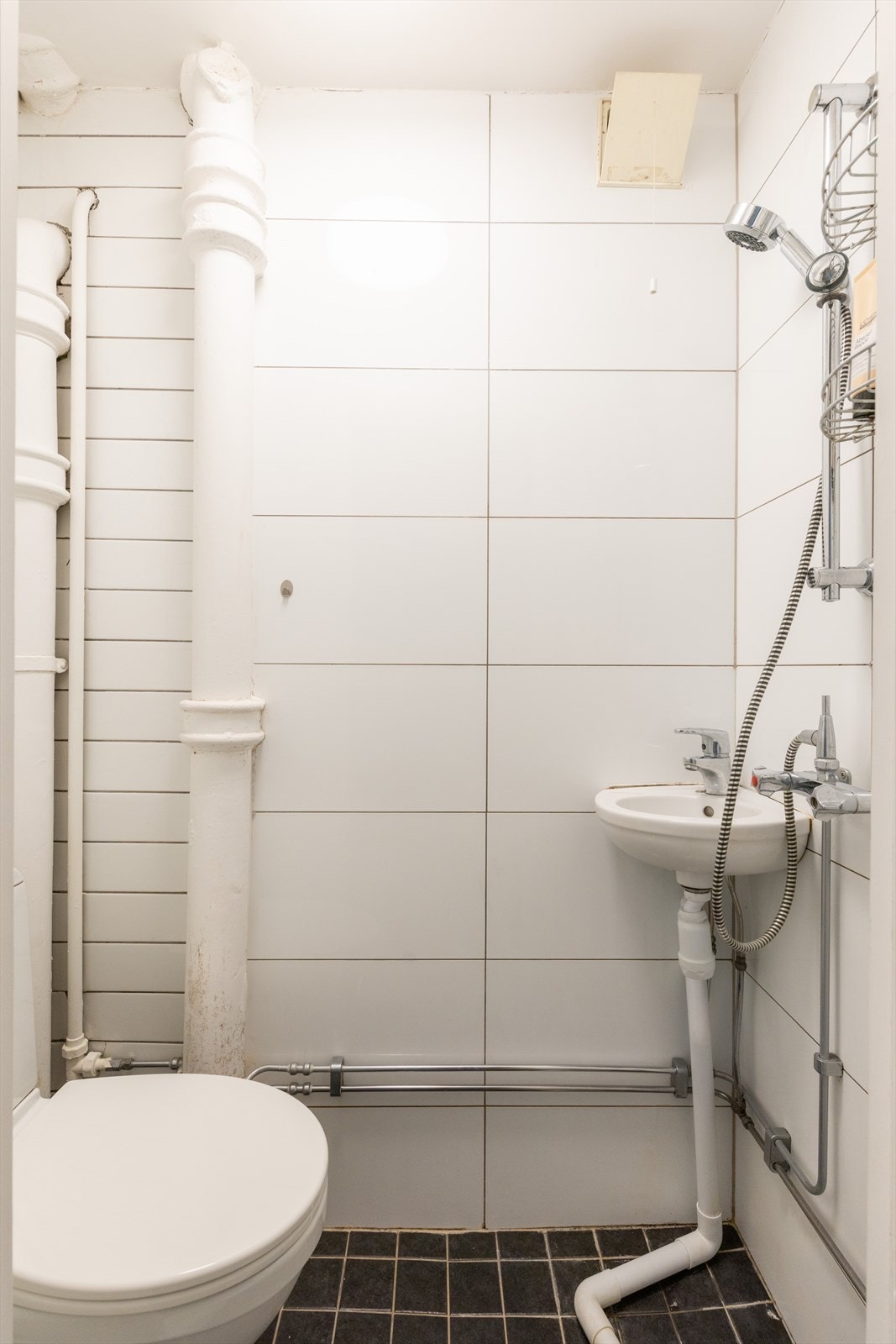 Badet er innredet med servant og toalett. Dusjen er plassert i hjørnet og har håndholdt dusjarmatur. Elektriske varmekabler er installert i gulvet. Galleribilde