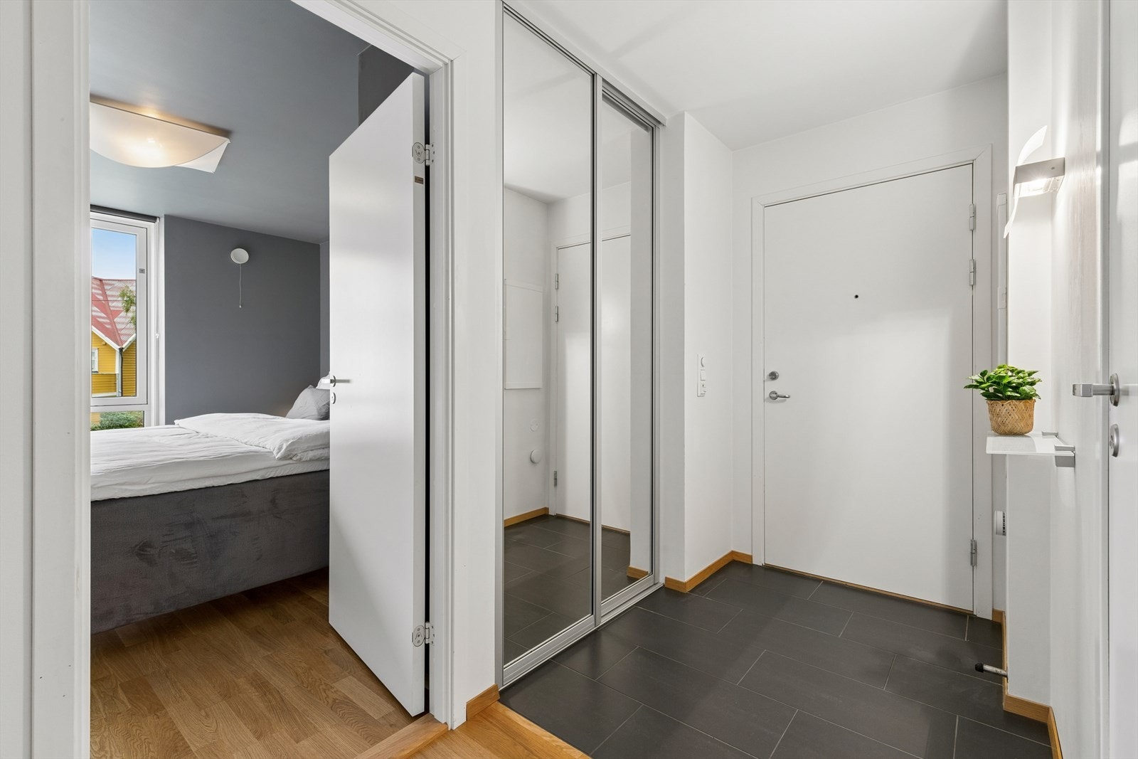 Entreen har mørke gulvfliser og skyvedørsgarderobe med speilfronter. Galleribilde