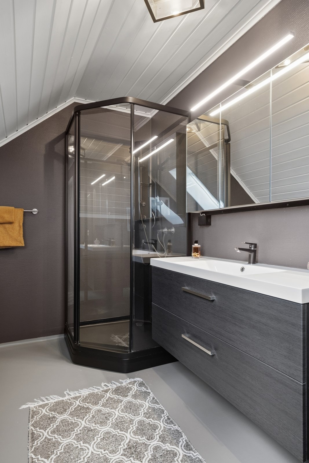 Badet er utstyrt med en nyere baderomsinnredning med servant, toalett, speilskap og god oppbevaringsplass i både skuffer og skap. I tillegg er det montert en romslig dusjkabinett med glassflater som understreker det moderne uttrykket. Galleribilde
