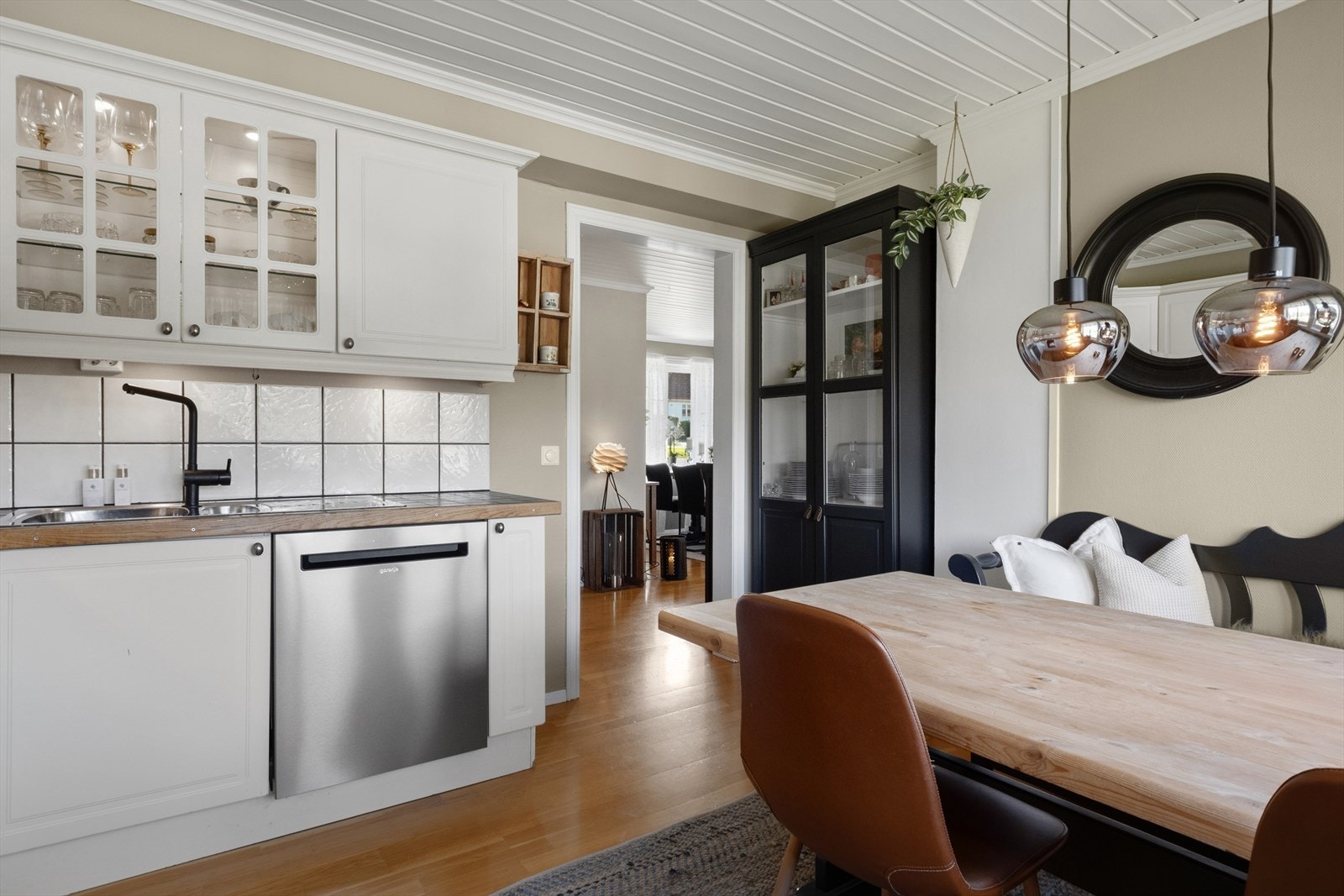 Innredningen har profilerte, hvite fronter som gir et tidløst og elegant uttrykk. Kjøkkenet er utstyrt med godt med skap- og skuffeplass, noe som gir praktiske oppbevaringsmuligheter og en ryddig arbeidsflate. Galleribilde