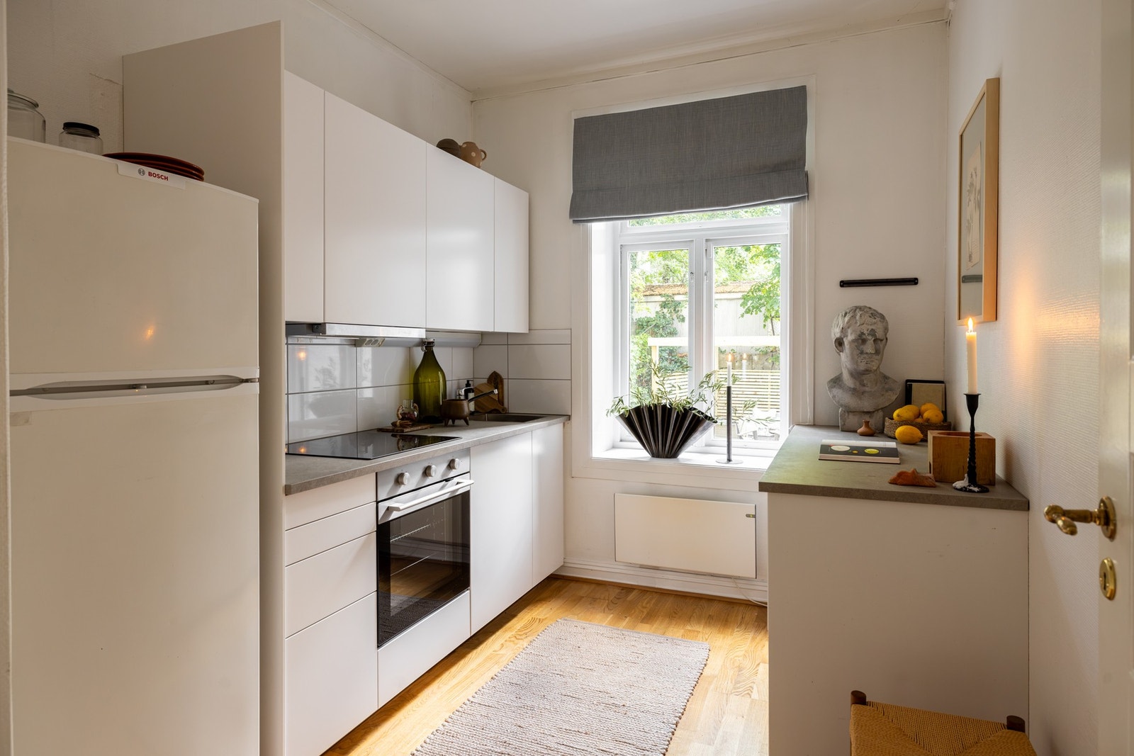 Kjøkkenet har en lys og tidløs innredning med glatte, hvite fronter, benkeplate og kum i rustfritt stål. Galleribilde
