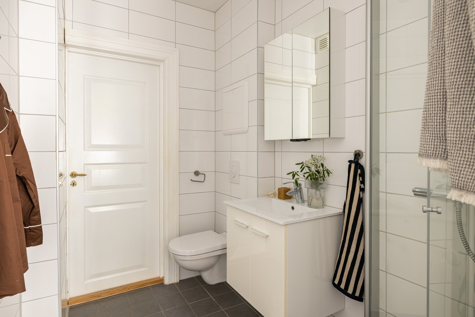 Badet er innredet med servant, benkeskap og speilskap, dusj med faste glassfelt og dør i herdet glass, samt vegghengt toalett med innebygget sisterne. Galleribilde