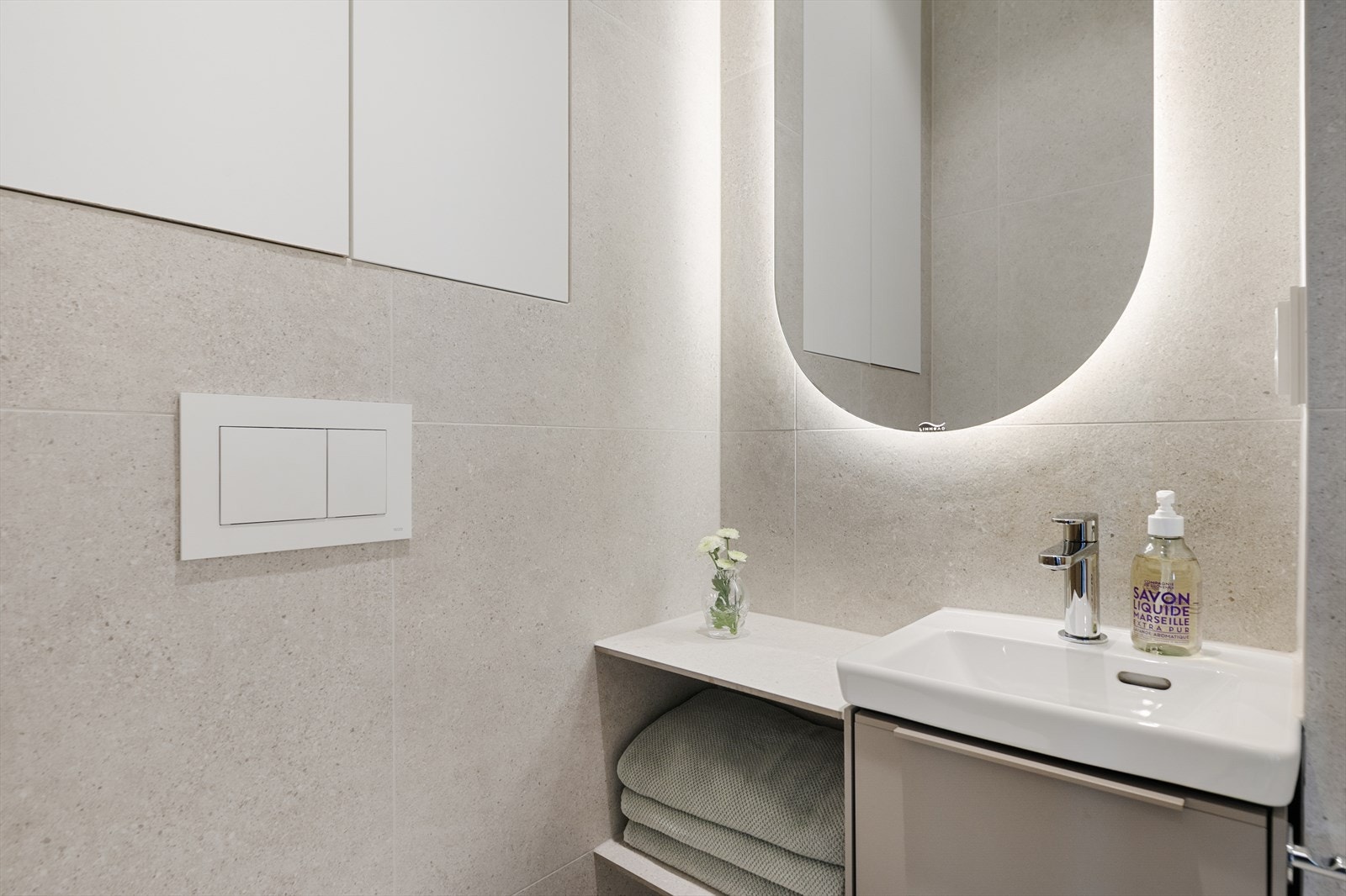 Badet er innredet med dusjplass med tilhørende garnityr, servant med underskap, speil med integrert belysning og vegghengt toalett. Galleribilde