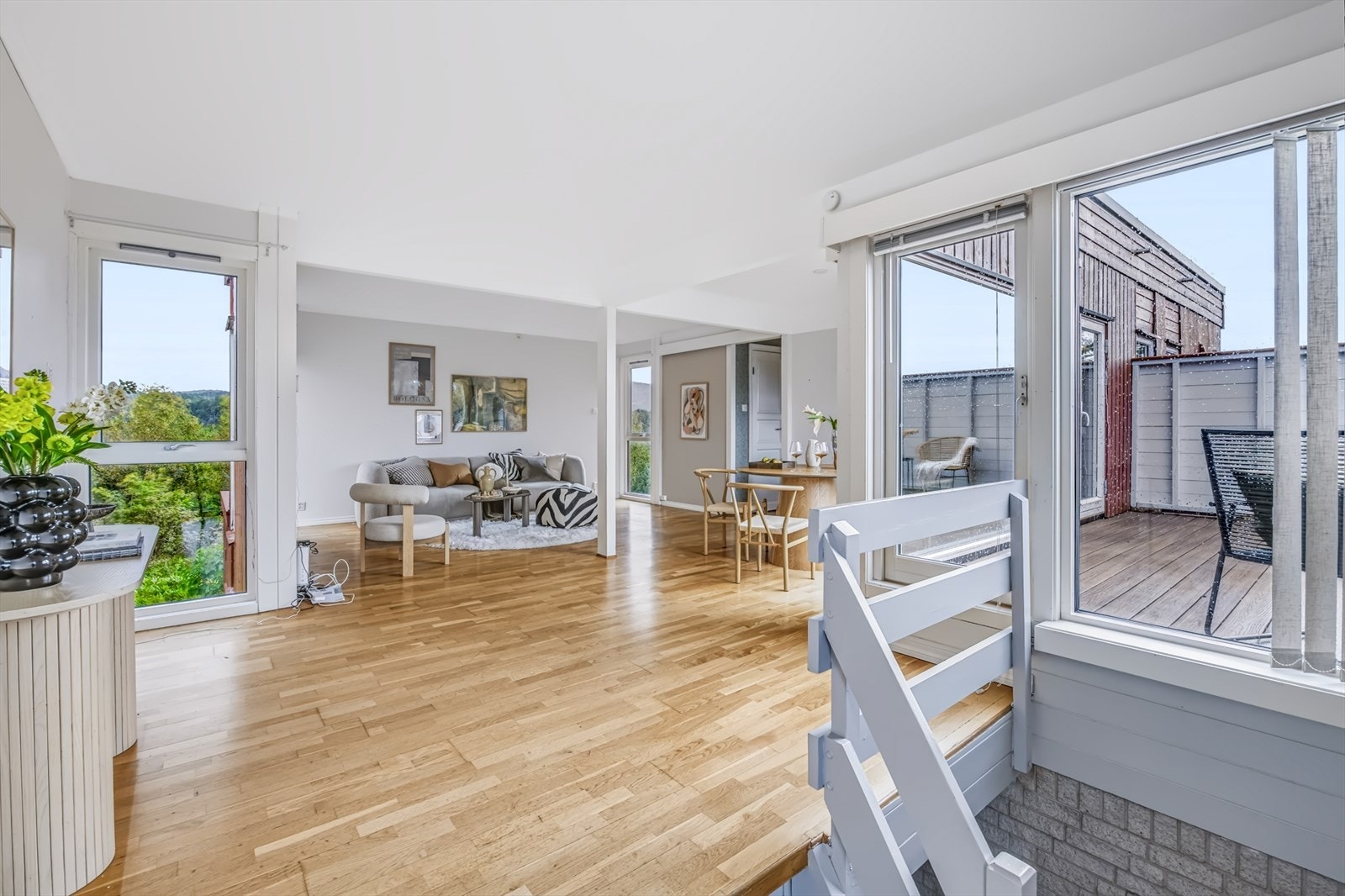 Velkommen inn i en lys og åpen stue med parkett på gulv og store vindusflater fra 2022 som gir rikelig med dagslys. Galleribilde