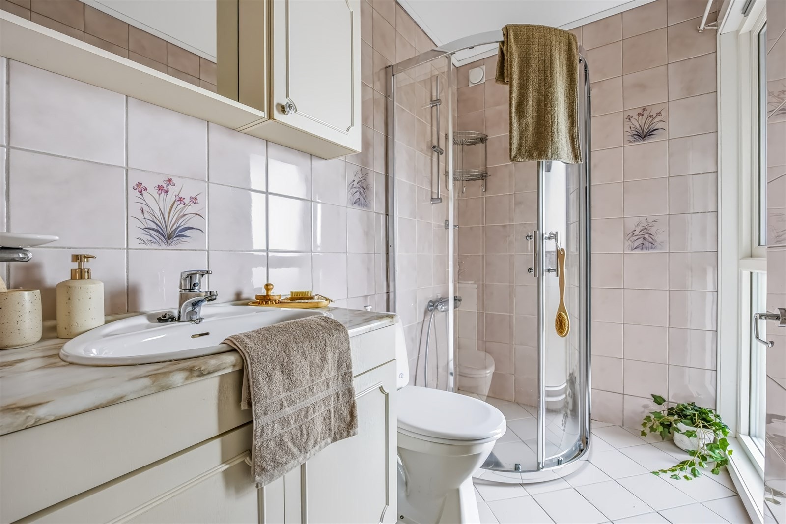 Badet har flislagte overflater, gulvvarme, baderomsinnredning og buet dusjhjørne. Galleribilde
