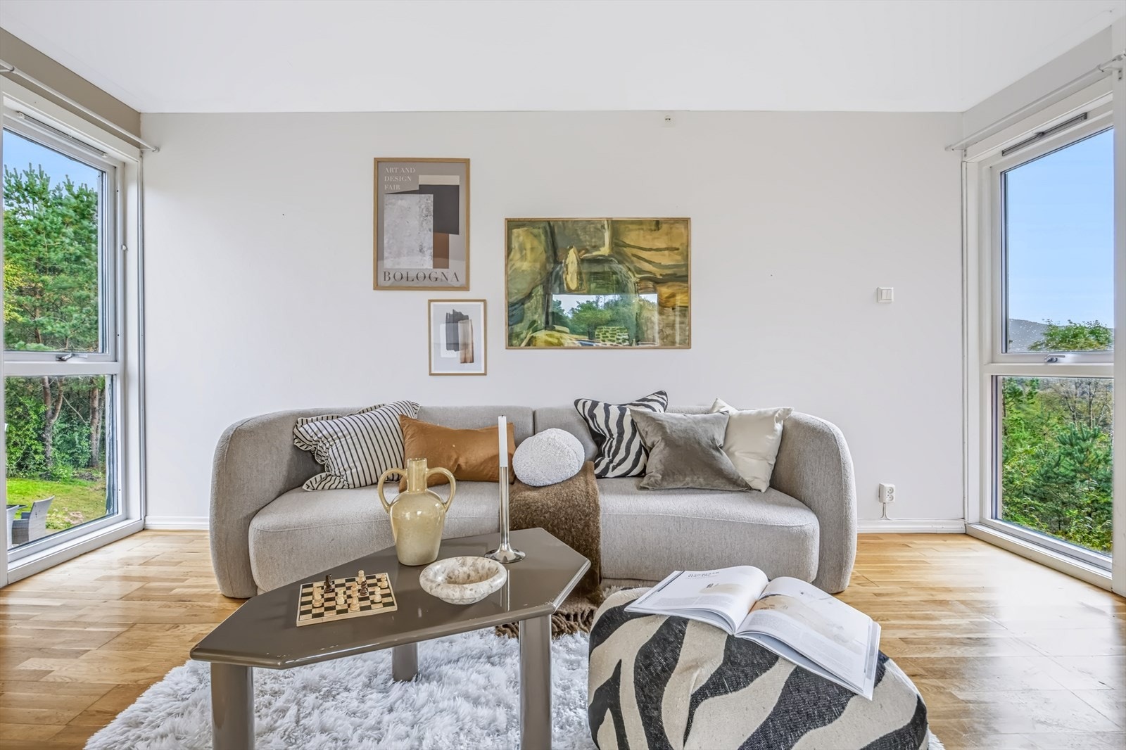 Sofagruppen er rammet inn av store vinduer omkranset av flotte grønområder. Galleribilde