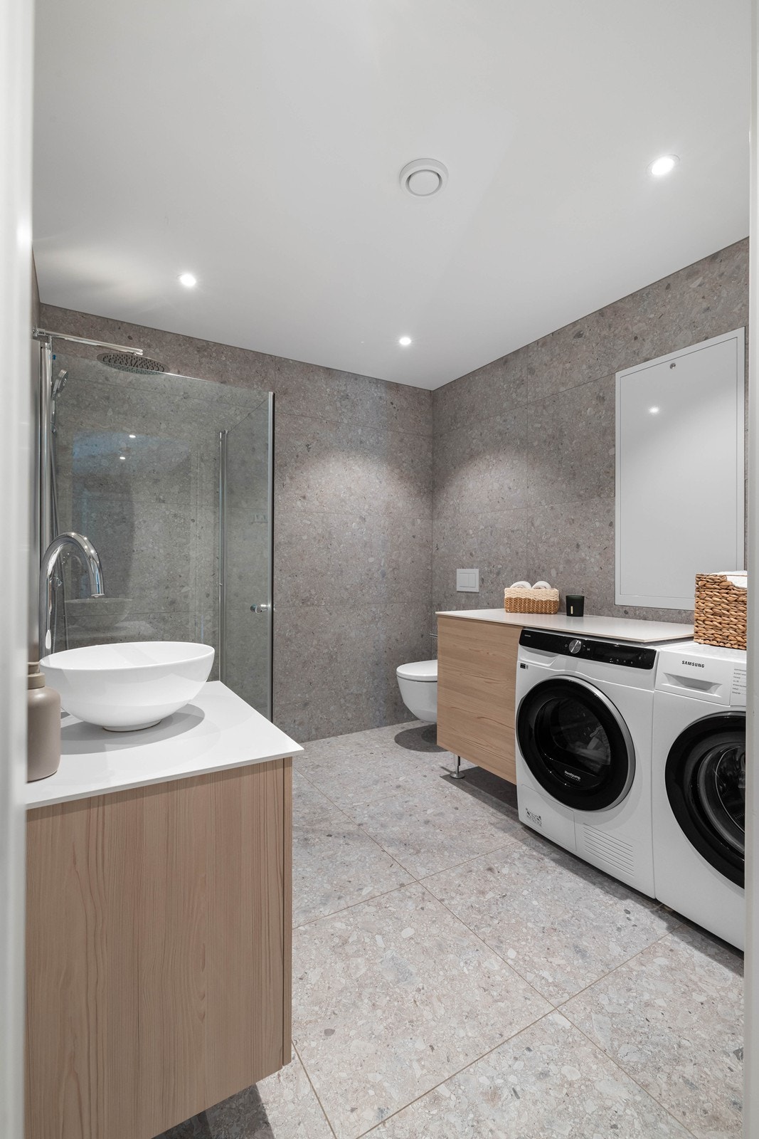 Badet i 1. etasje er innredet med toppmontert servant og har innredning av veggmontert toalett, dusjvegger/hjørne og opplegg for vaskemaskin og tørketrommel. Galleribilde