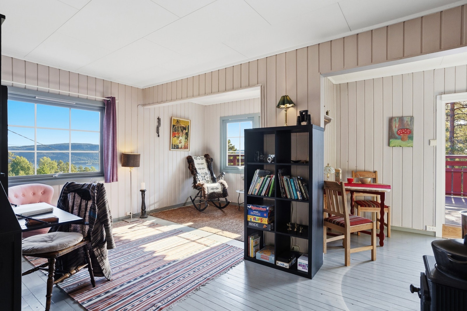 Lys og hyggelig stue med malt tregulv, panel på vegger og takplater i himling Galleribilde