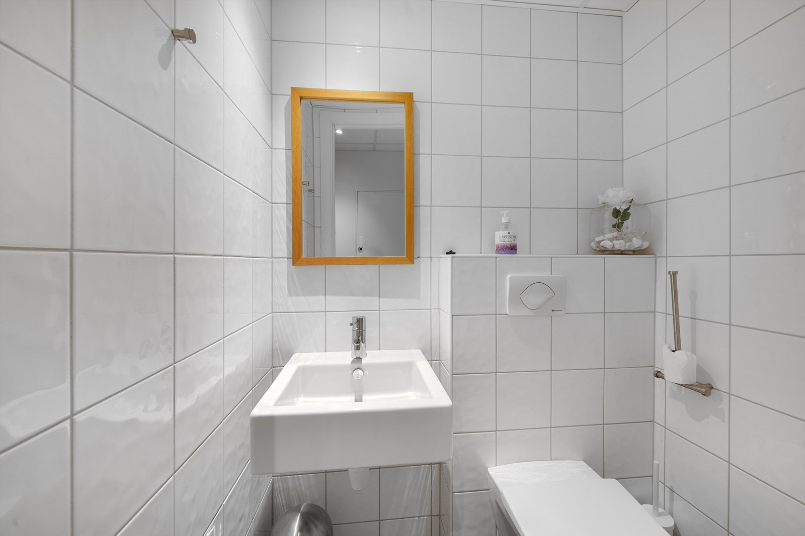 Separat toalettrom med vegghengt toalett, innebygd sisterne og liten servant. Galleribilde