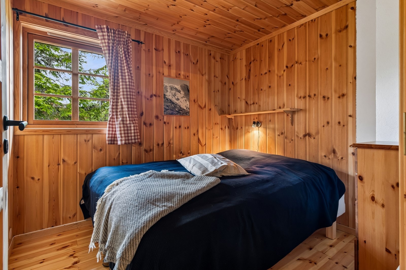 Soverom med tregulv, panelkledde vegger og plass til dobbeltseng. Galleribilde