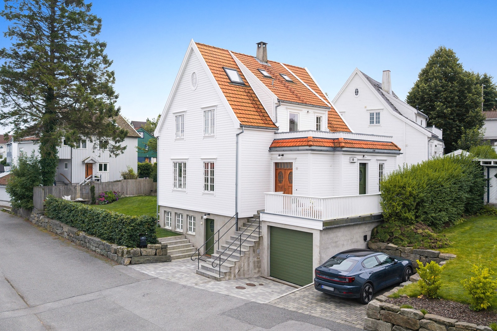 Steinbelagt gårdsplass gir et pent og praktisk adkomstområde, mens en medfølgende robotgressklipper med ladestasjon gjør plenstellet enkelt. Galleribilde