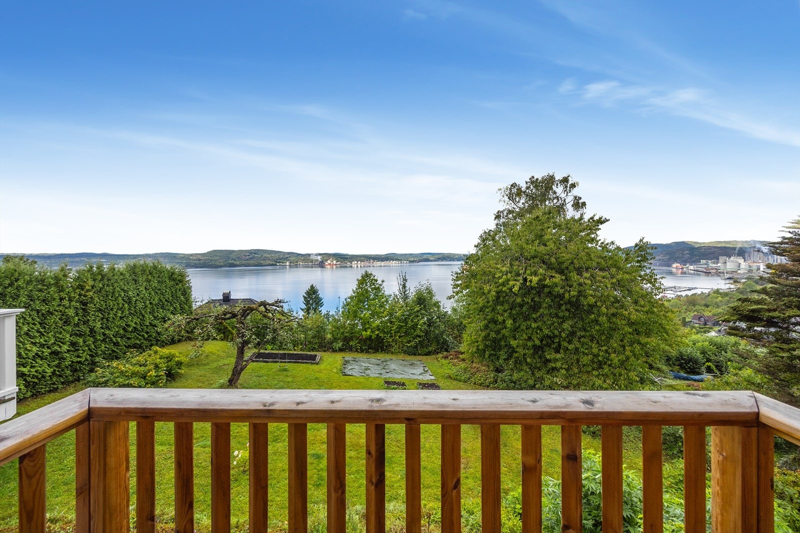 Utsyn fra balkongen ned mot den grønne hagen og fjorden. Galleribilde