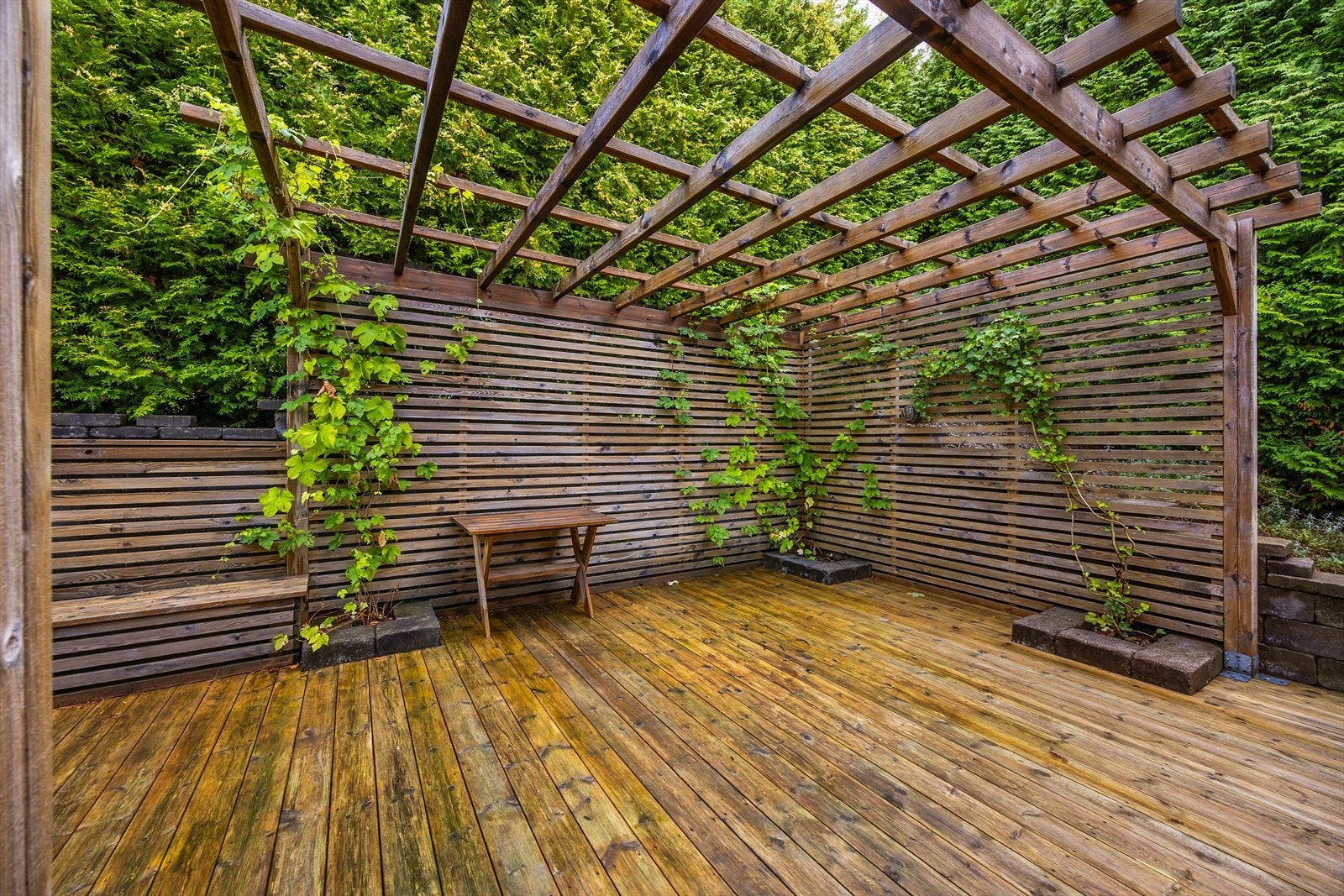 Treplatting med pergola og spilevegger danner en lun uteplass. Galleribilde