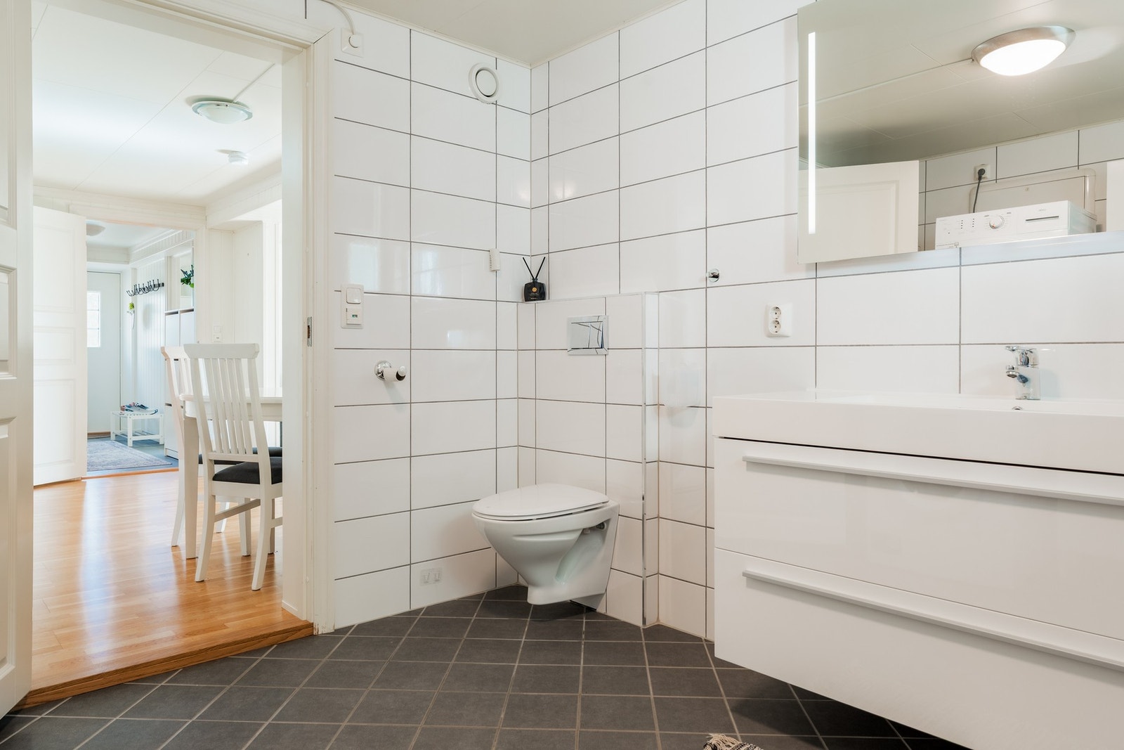 Badet måler hele 8,4 m² og har flislagte vegger og mørkere fliser på gulvet. Galleribilde