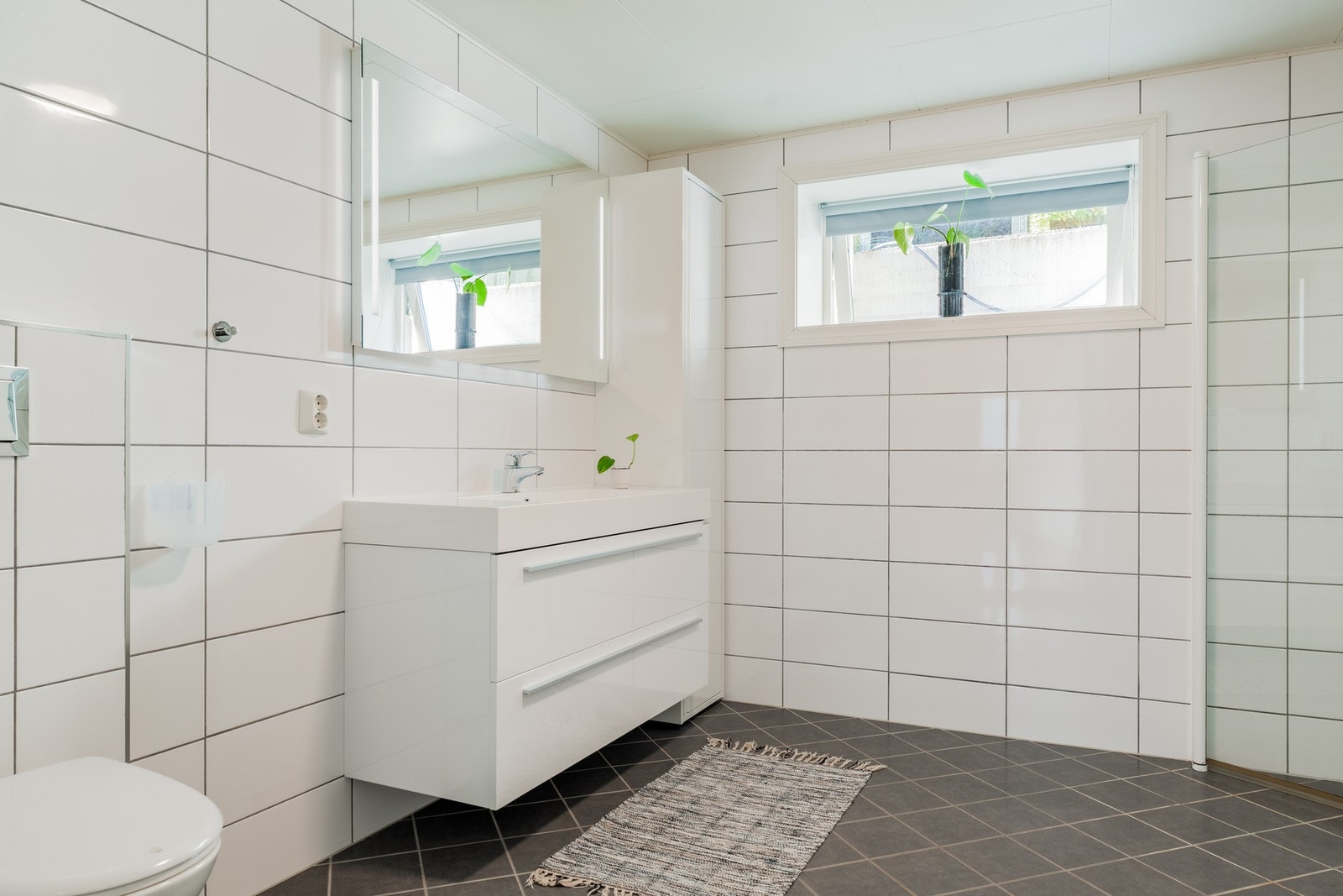 Badet er innredet med vegghengt toalett og dusjsone med klare glassdører. Galleribilde