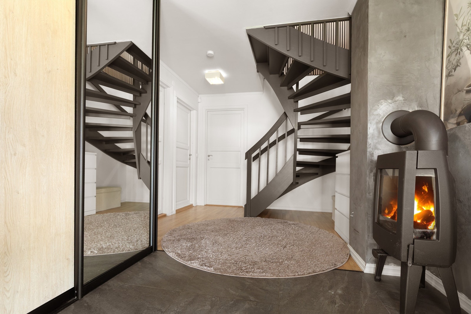 Praktisk skyvedørsgarderobe med speildører og peisovn som varmer etasjen. Galleribilde