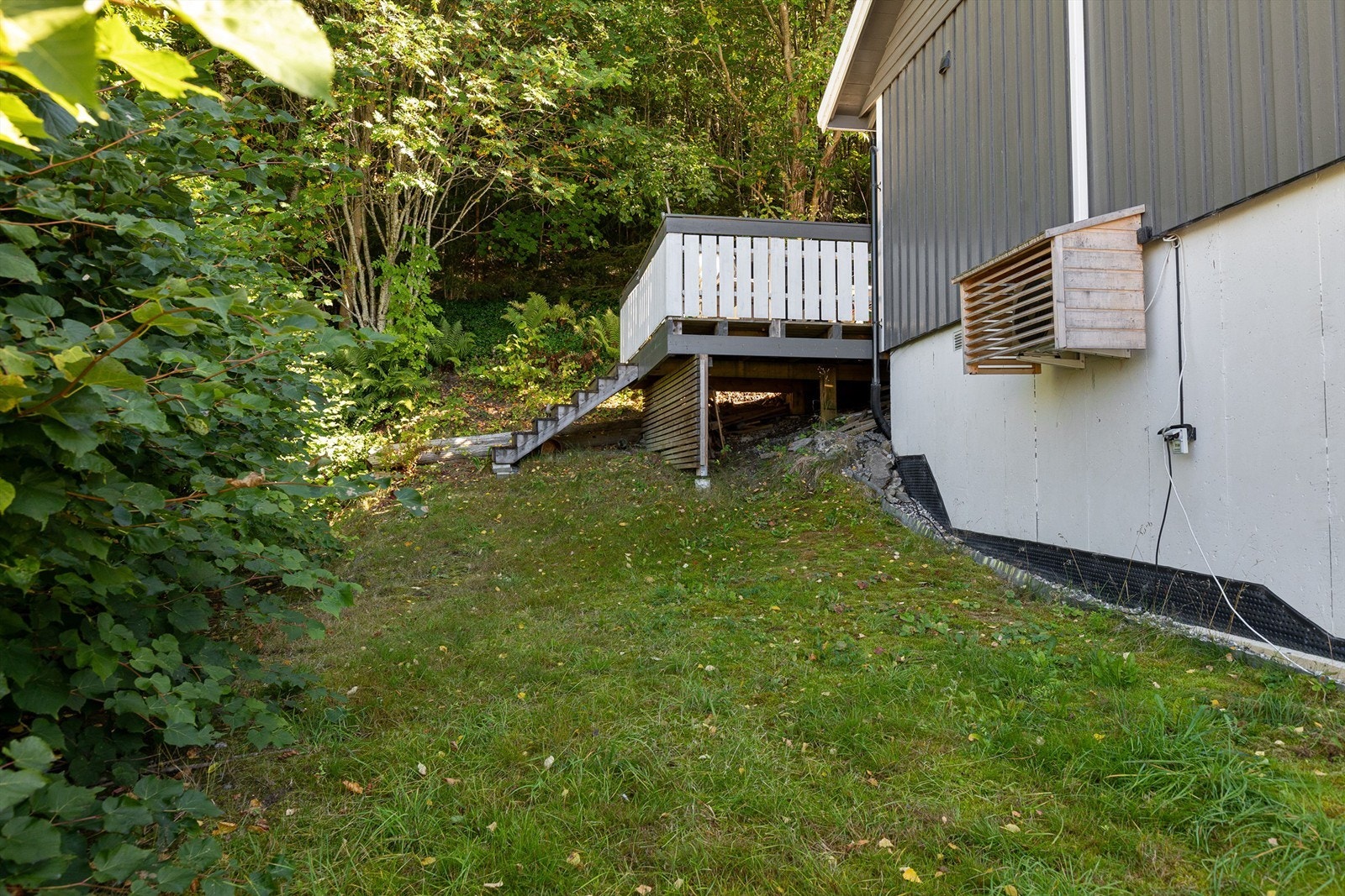 Skrånende tomt opparbeidet med plenareal og trapp opp til terrassen. Galleribilde