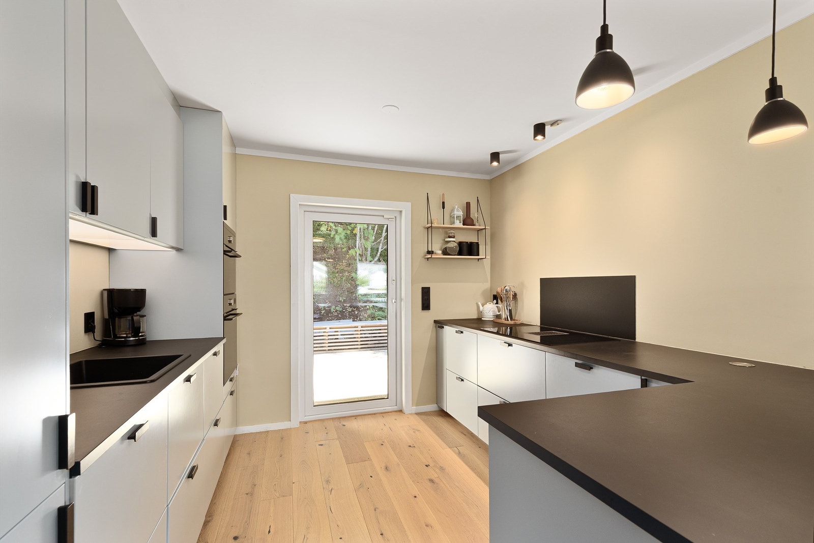 Glatte fronter, laminert benkeplate og glassplate montert bak vask og platetopp. Galleribilde