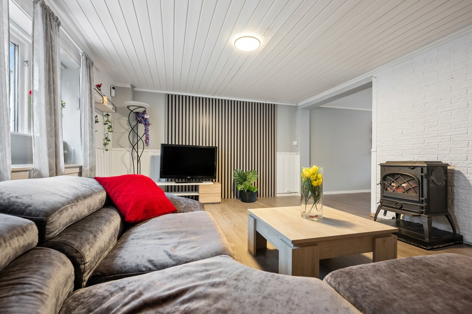 Stuen fremstår lyst og innbydende med laminatgulv, panel i himlingen og malte veggflater med dekorative innslag av murt forblending og moderne spilefelt. Galleribilde