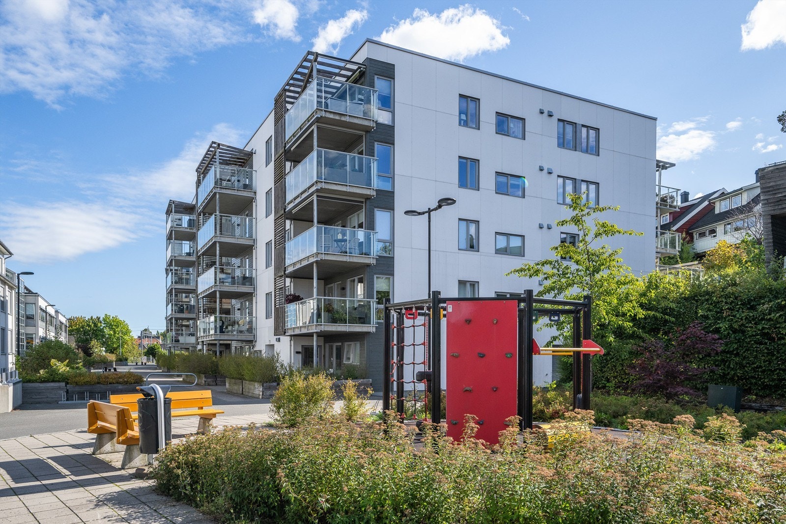 Skjermet gårdsrom med sittebenker og lekeapparater for beboerne. Galleribilde