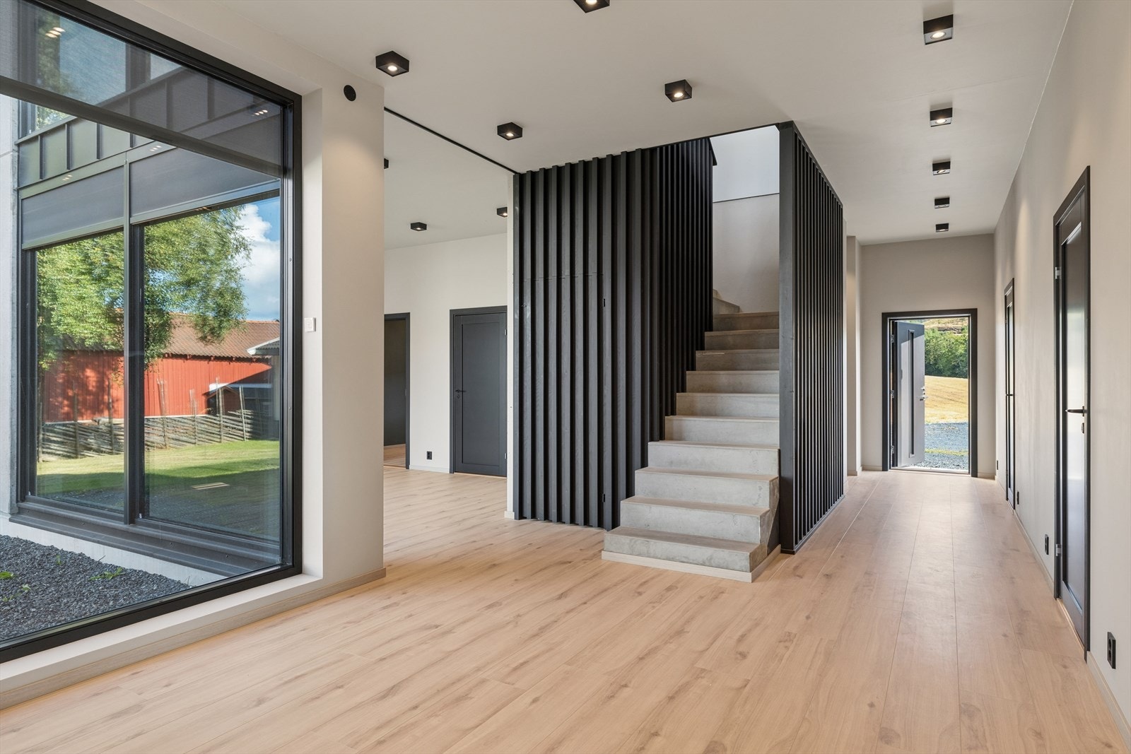Fra entréen ledes man inn i en romslig etasje med laminatgulv og malte overflater. Boligens materialkonsept kommer tydelig til uttrykk allerede ved inngangen og spilerekkverket rundt trappen definerer tilkomsten til boligens andre etasje. Galleribilde